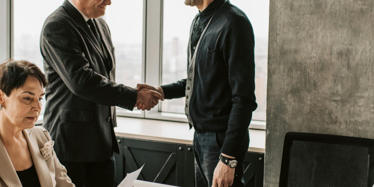 Two professionals shake hands, symbolizing a strong partnership and trust in navigating complex compliance requirements.