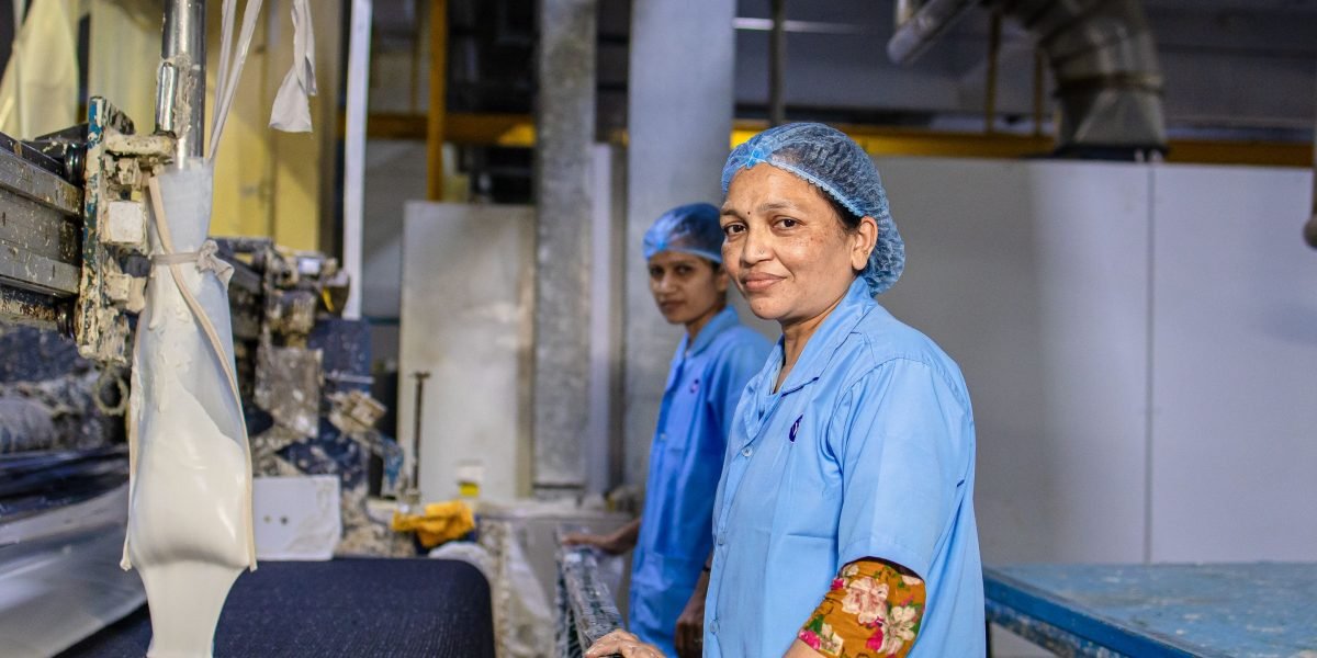 Workers in a historical factory setting, operating large machinery typical of the Industrial Revolution era.
