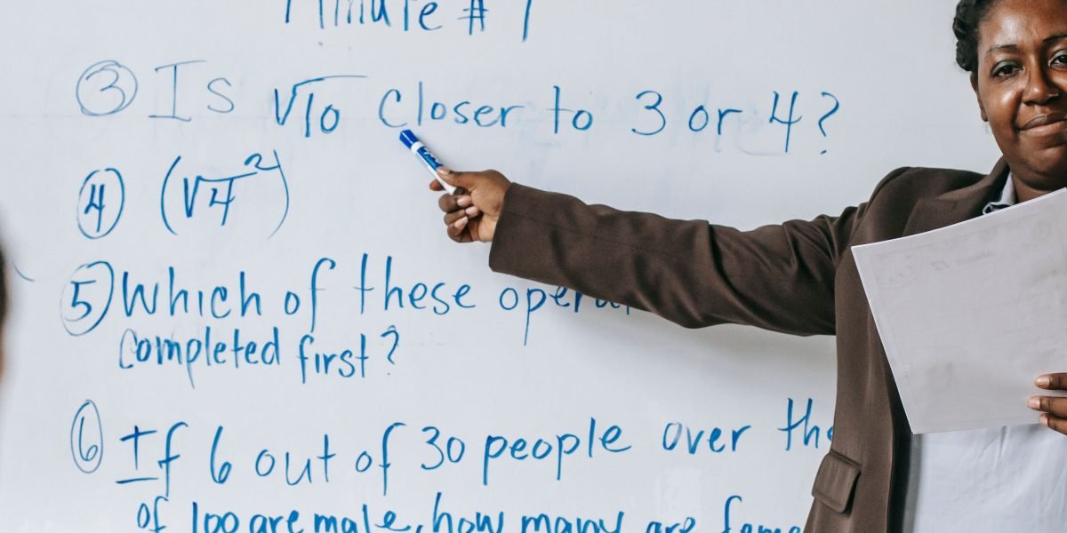An instructor or team member clarifying ideas on a whiteboard, illustrating the non-technical explanation of AI learning.