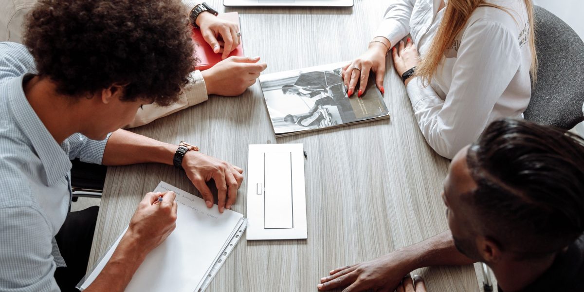 A small team engaged in a collaborative discussion around a table, symbolizing their effort to track and understand compliance rules.