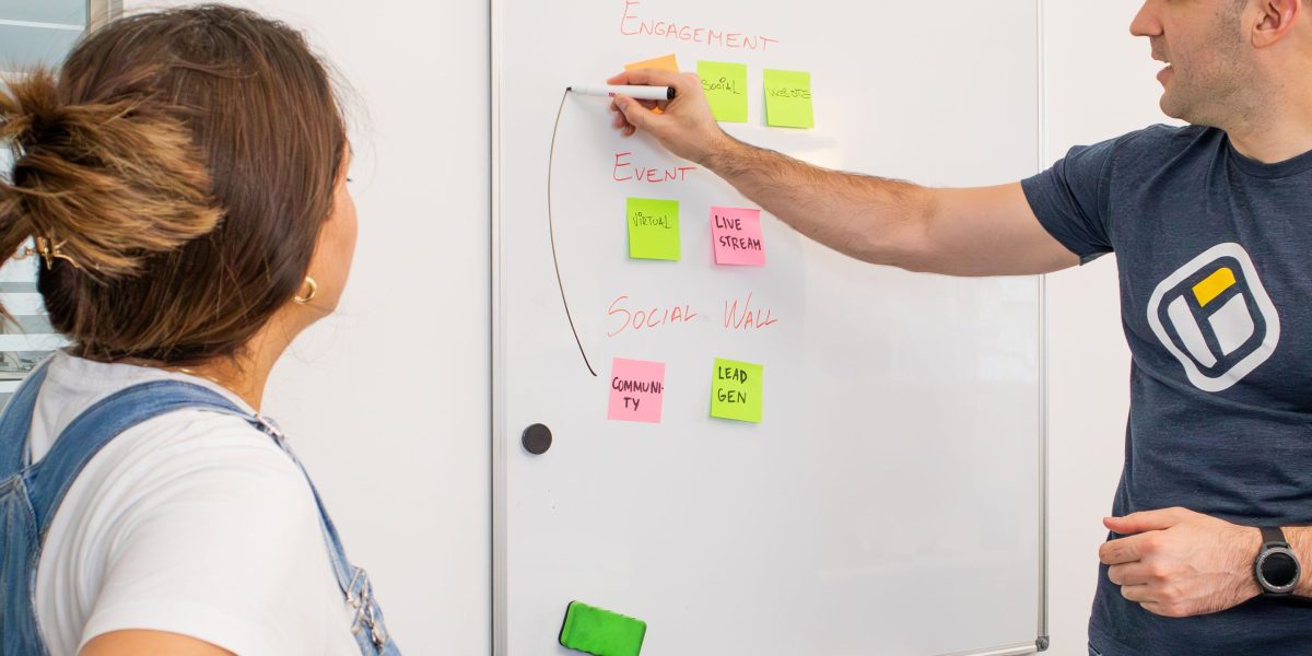 A group of professionals actively brainstorming and mapping out complex system architectures on a whiteboard, symbolizing the design of AI agents.