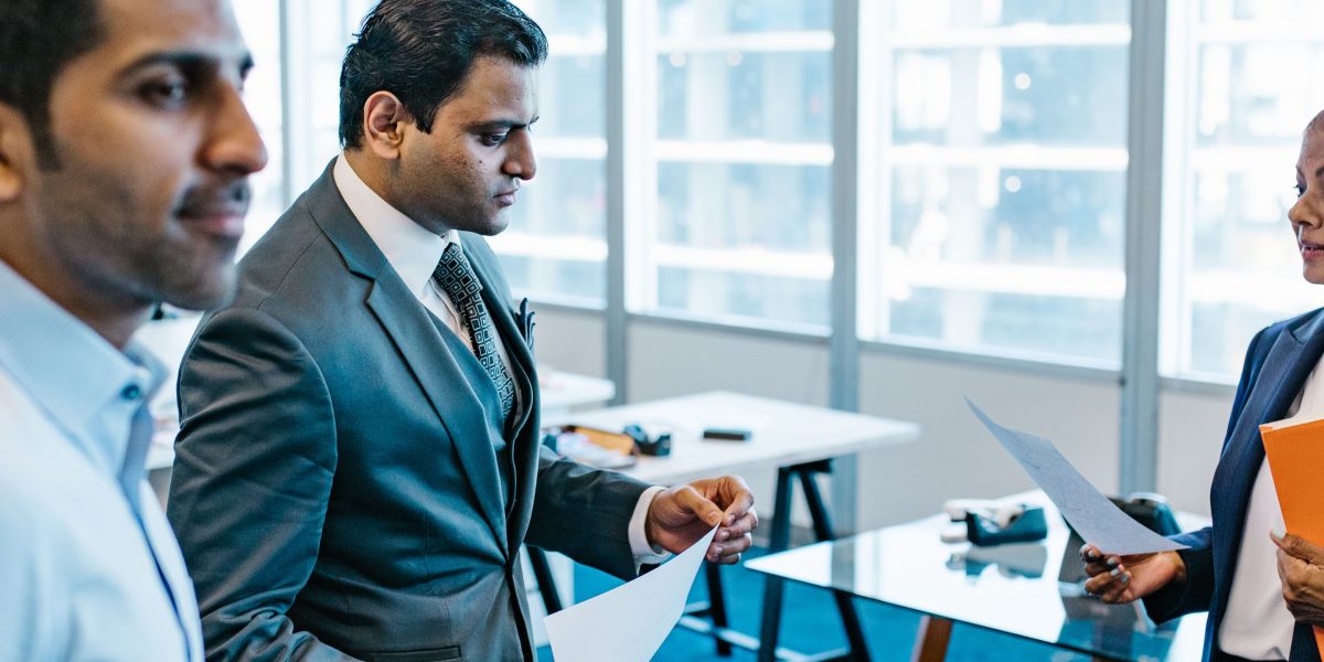 A group of executives in a formal meeting, intently reviewing documents related to governance, risk, and compliance for AI systems.