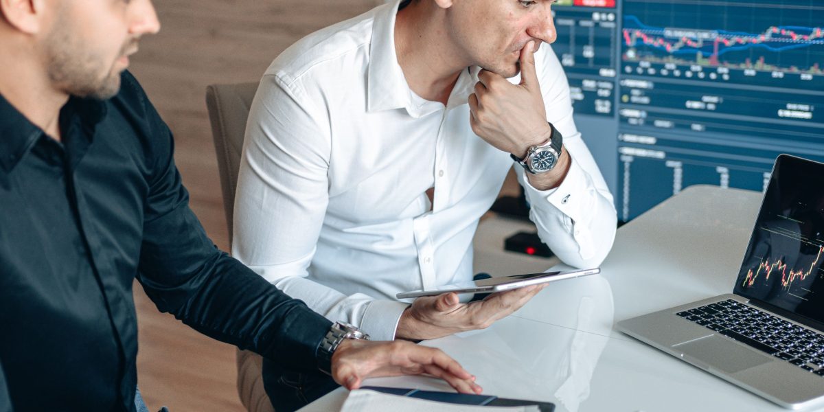 Investors and business leaders analyzing market data and financial charts to gauge AI's impact.